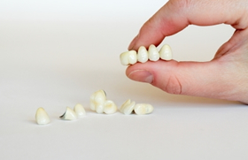 picture of a hand holding dental crowns 